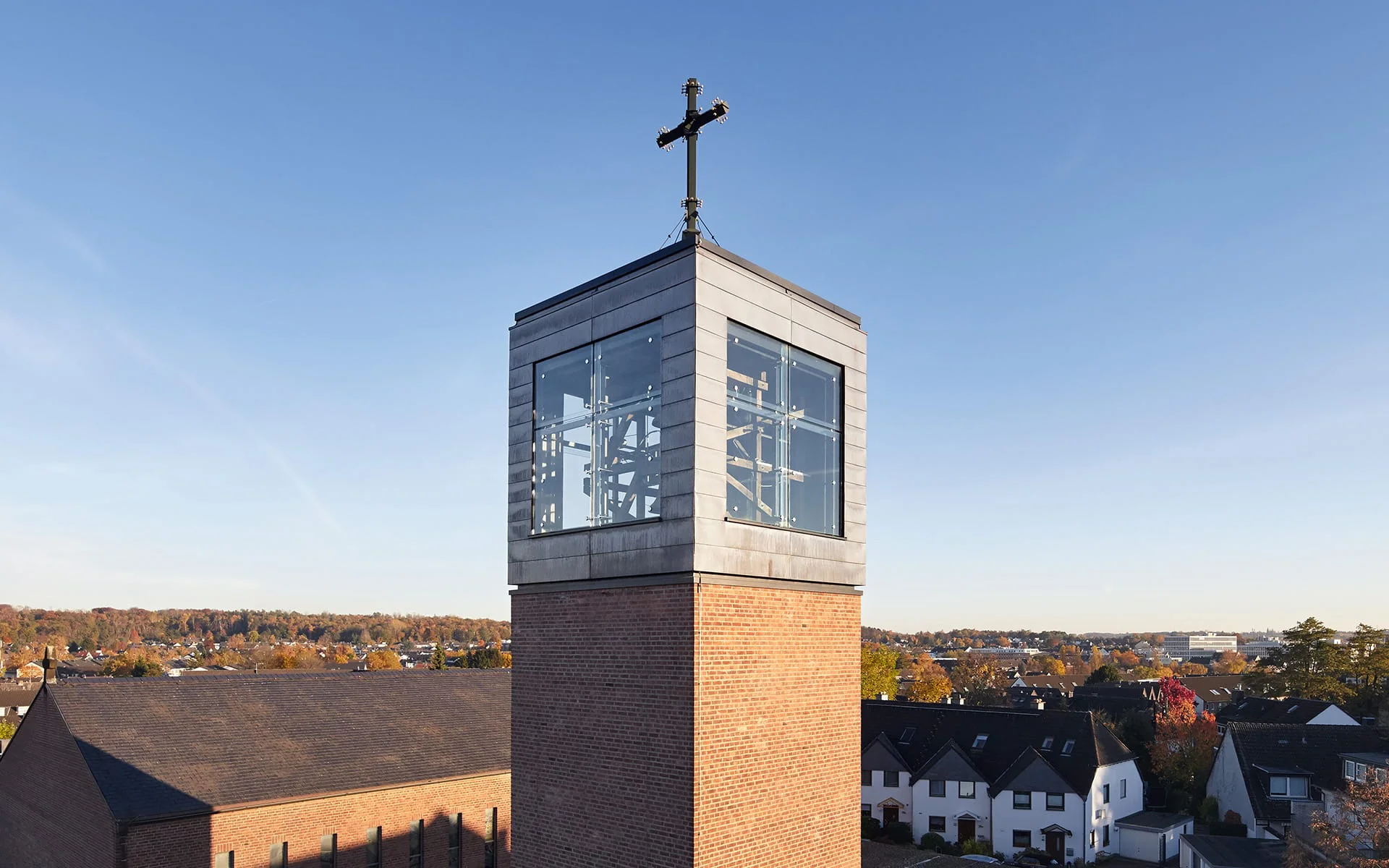 Glockenturm mit Glaswürfel oben, großes Kreuz als Spitze