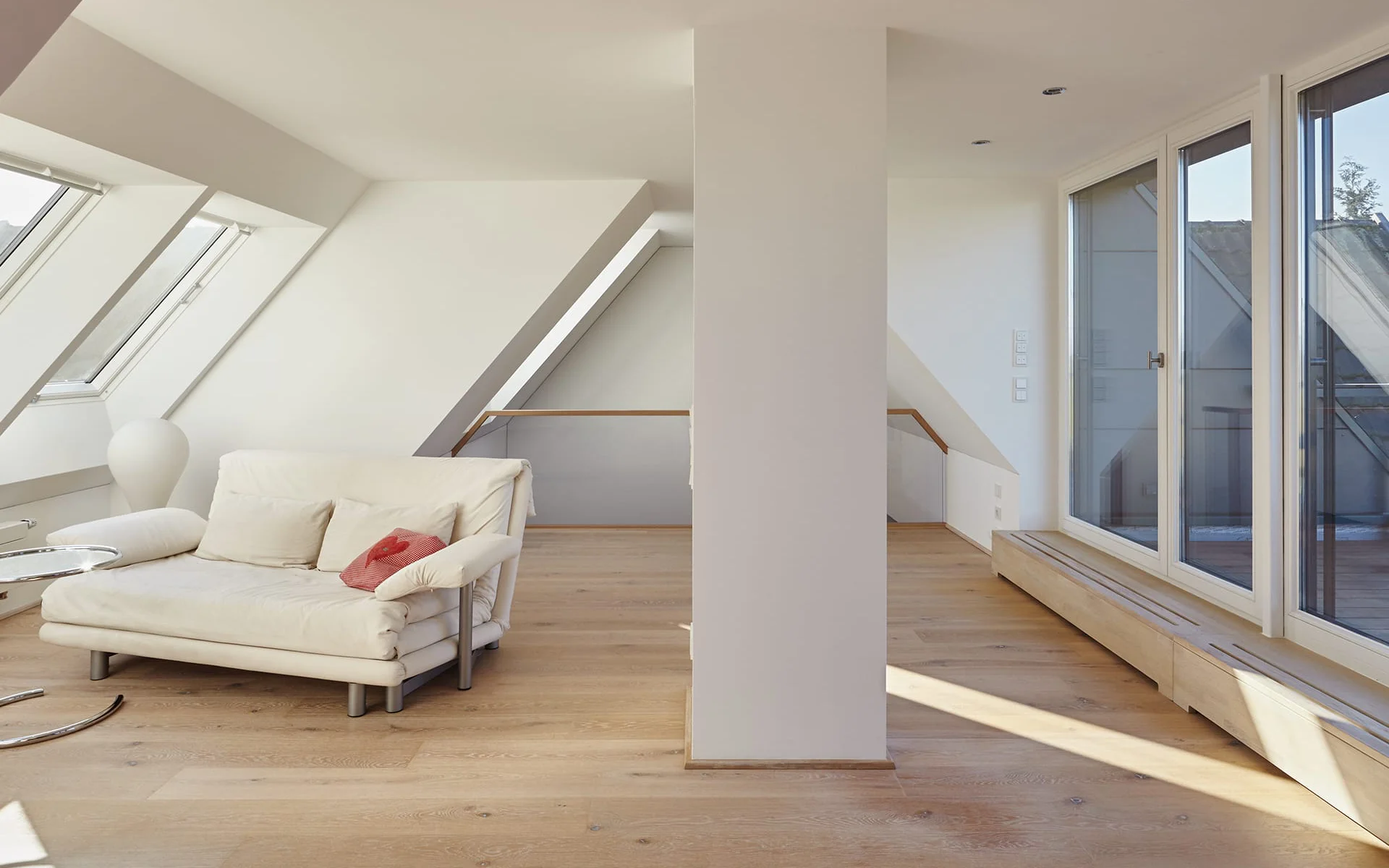 Sofa in einem Raum mit Dachschräge und Fensterfront an beiden Seiten